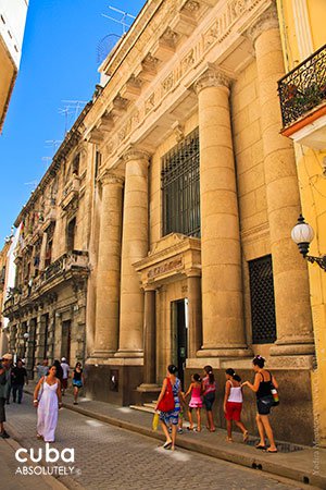 People walking by the Front of Numismatic museum, yellow building © Cuba Absolutely, 2014