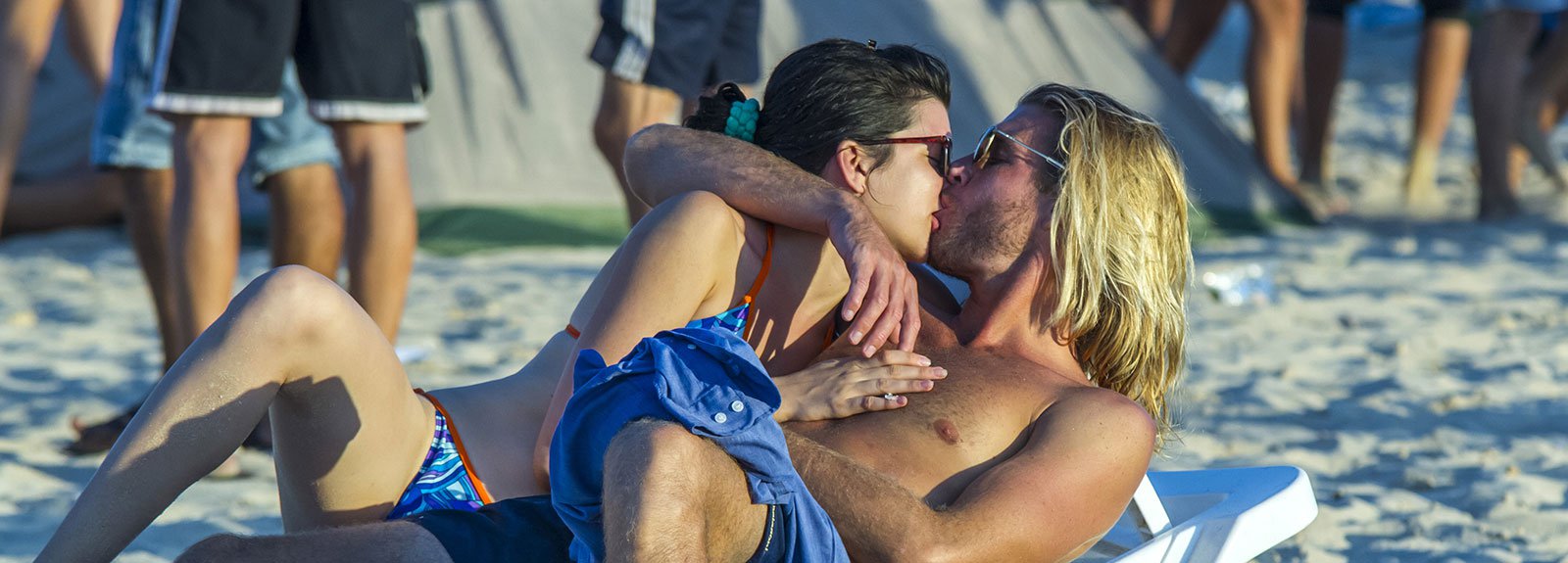 Blond boy kissing a girl on a white bank at the beach